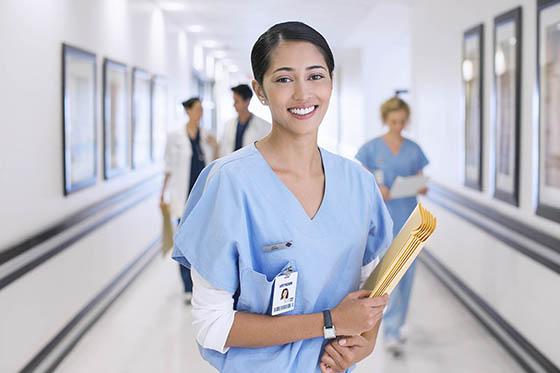 一名穿着蓝色手术服的护士拿着病人的档案，微笑着拍照